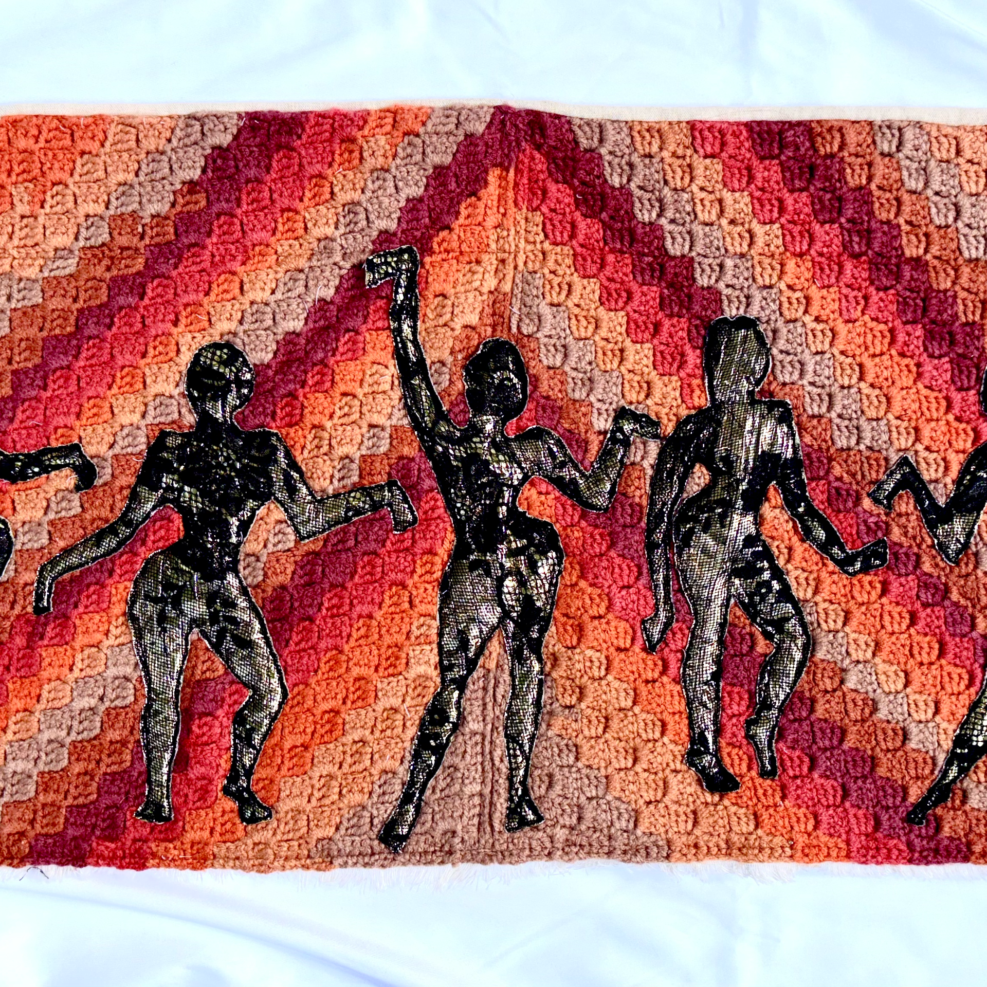 Fiber art piece depicting dancing ladies in colorful textile