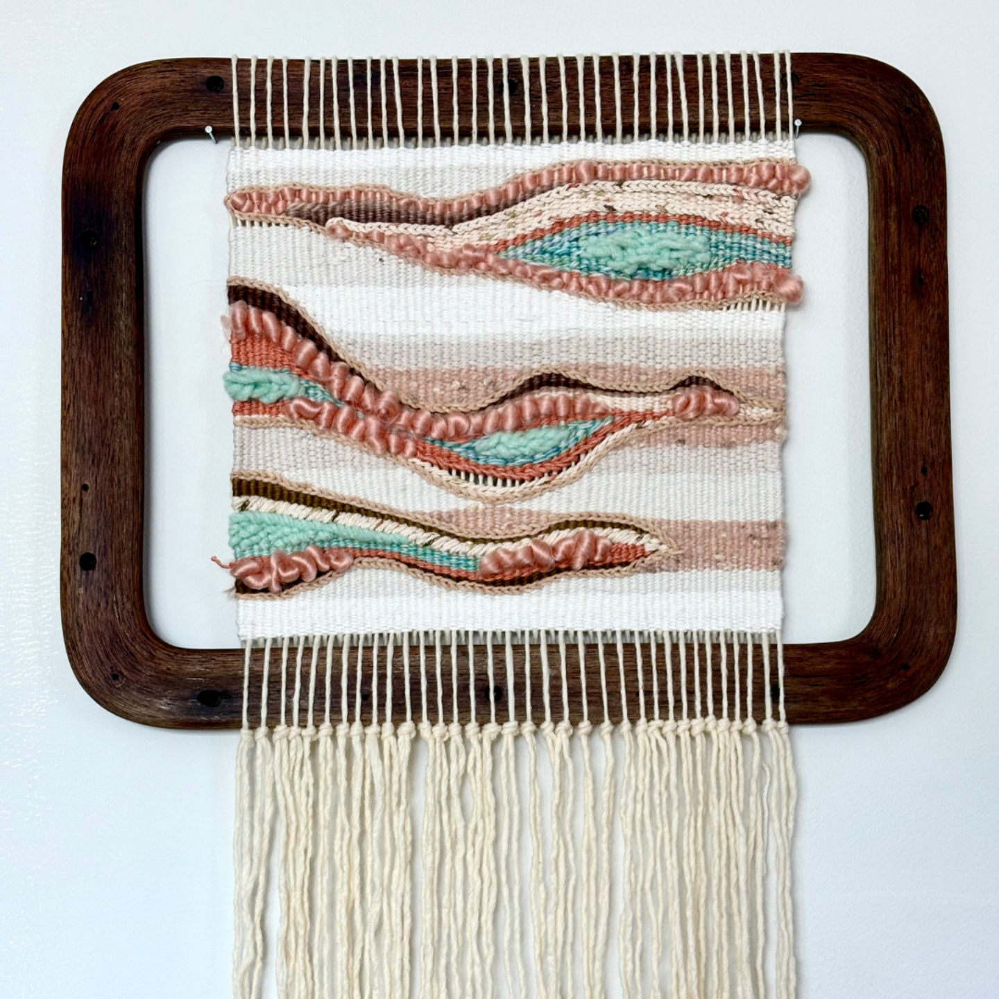 a piece of handmade fiber art in a wood frame